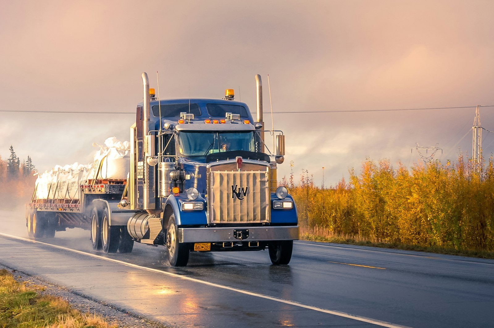 Blue hotshot truck hauling a flatbed load on the highway